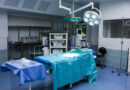 Vista de sala de cirurgia composta por uma maca, itens de bisturi e equipamentos cirúrgicos