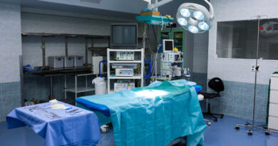 Vista de sala de cirurgia composta por uma maca, itens de bisturi e equipamentos cirúrgicos